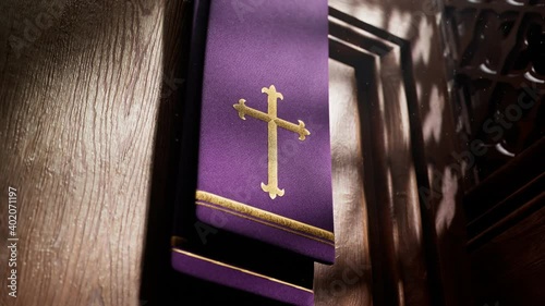Purple stole with cross lightened by rays of light falling into a confessional.