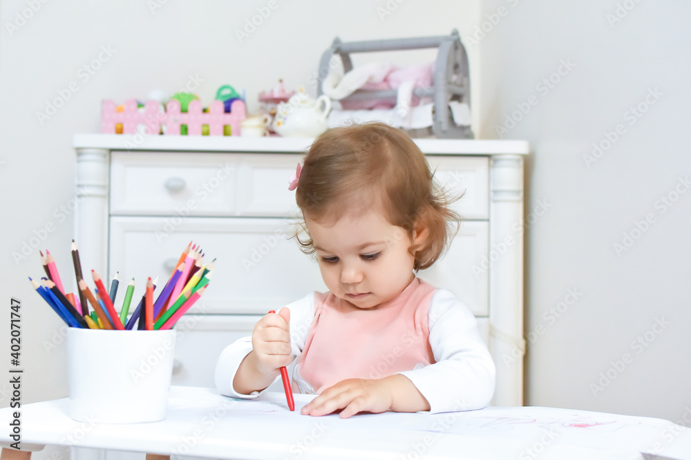 Cute adorable baby girl drawing a picture with colored pencil at home or kindergarten. Toddler child painting on paper. Kid playing in nursery. Cute adorable baby girl drawing a picture with colored pencil at home or kindergarten. Toddler child painting on paper. Kid playing in nursery.
