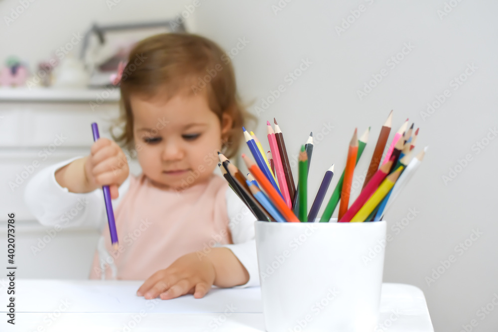 Cute adorable baby girl drawing a picture with colored pencil at home or kindergarten. Toddler child painting on paper. Kid playing in nursery. Cute adorable baby girl drawing a picture with colored pencil at home or kindergarten. Toddler child painting on paper. Kid playing in nursery.