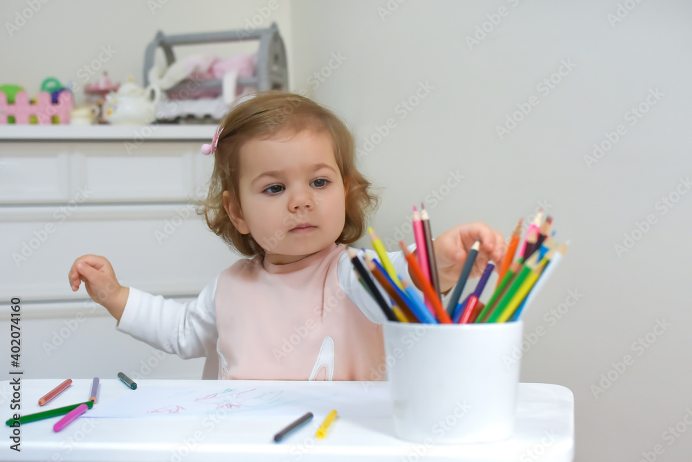 Cute adorable baby girl drawing a picture with colored pencil at home or kindergarten. Toddler child painting on paper. Kid playing in nursery. Cute adorable baby girl drawing a picture with colored pencil at home or kindergarten. Toddler child painting on paper. Kid playing in nursery.