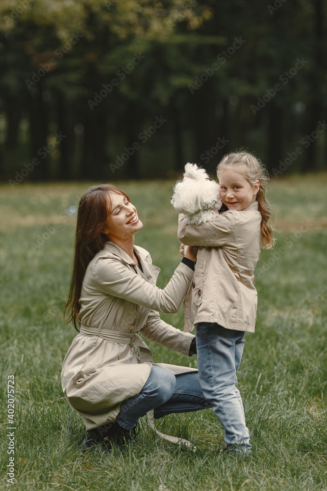 Mother and her daughter playing with dog. Family in autumn park. Pet, domestic animal and lifestyle concept. Autumn time. Mother and her daughter playing with dog. Family in autumn park. Pet, domestic animal and lifestyle concept. Autumn time.