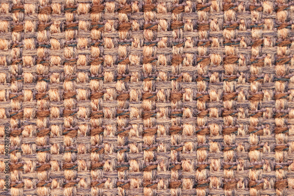 A sample of beige-brown woolen fabric with textured and pronounced weave of threads. Textiles and wool. Blank background and close-up. A sample of beige-brown woolen fabric with textured and pronounced weave of threads. Textiles and wool. Blank background and close-up.