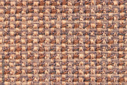 A sample of beige-brown woolen fabric with textured and pronounced weave of threads. Textiles and wool. Blank background and close-up.