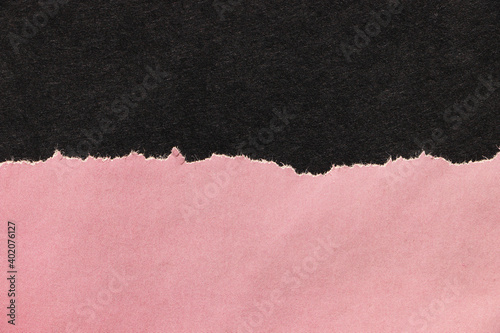 Ragged edges of pink paper on black surface. Empty background.	