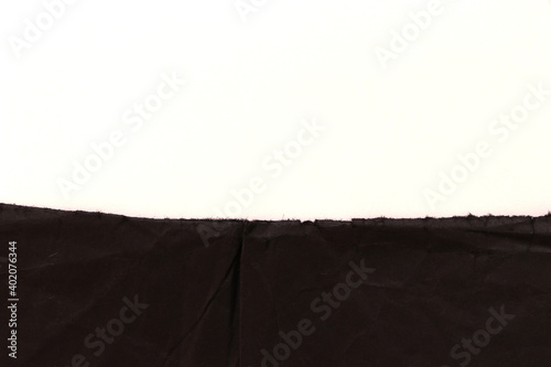 Torn edge of black paper on white background. Empty backdrop.