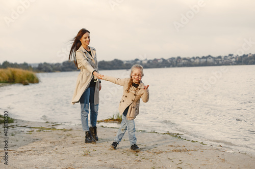 Fashionable mother with daughter. People walks outside. Woman in a brown coat.