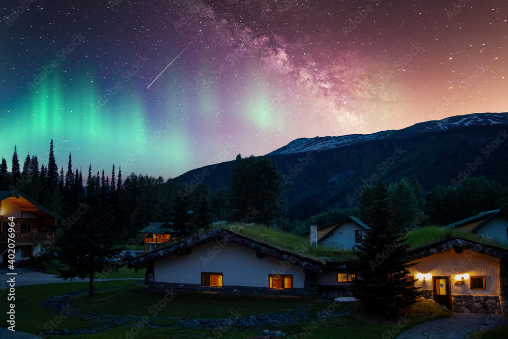 Fototapeta premium Milky way stars and northern lights auras over small village homes
