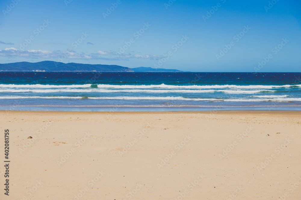 pristine wild landscape at Clifton Beach in Tasmania, Australia with wavy blue ocean and golden sand next to a rugged coastline pristine wild landscape at Clifton Beach in Tasmania, Australia with wavy blue ocean and golden sand next to a rugged coastline