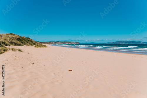 pristine wild landscape at Clifton Beach in Tasmania  Australia with wavy blue ocean and golden sand next to a rugged coastline