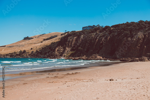 pristine wild landscape at Clifton Beach in Tasmania, Australia with wavy blue ocean and golden sand next to a rugged coastline