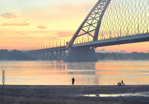 Fisherman on the beach. Car Bugrinskij bridge across the Great Siberian river Ob in the morning mist photo