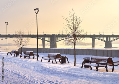 Fototapeta Naklejka Na Ścianę i Meble -  Michael's embankment in winter. Benches along the pedestrian alley, Oktyabrsky bridge in the distance