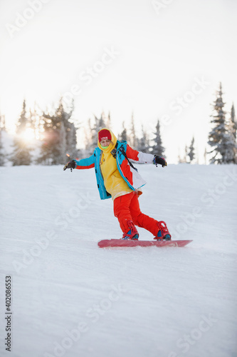 Woman is snowboarding on the snowy slopes.