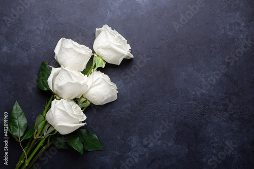 Fototapeta Naklejka Na Ścianę i Meble -  White rose flowers bouquet on black stone background. Greeting card with copy space for text