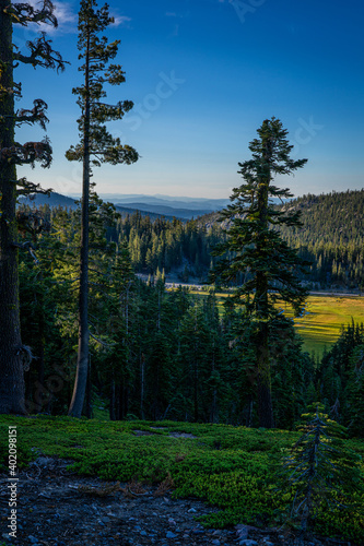 This is an early morning view of the wilderness of Lassen Volcanic National Park in northern California. Mountains, meadows, and pine forests are seen.