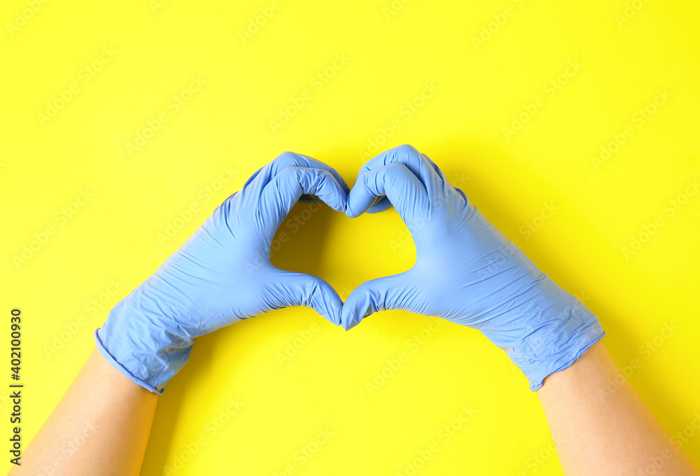 Hands in protective gloves making heart on color background Hands in protective gloves making heart on color background