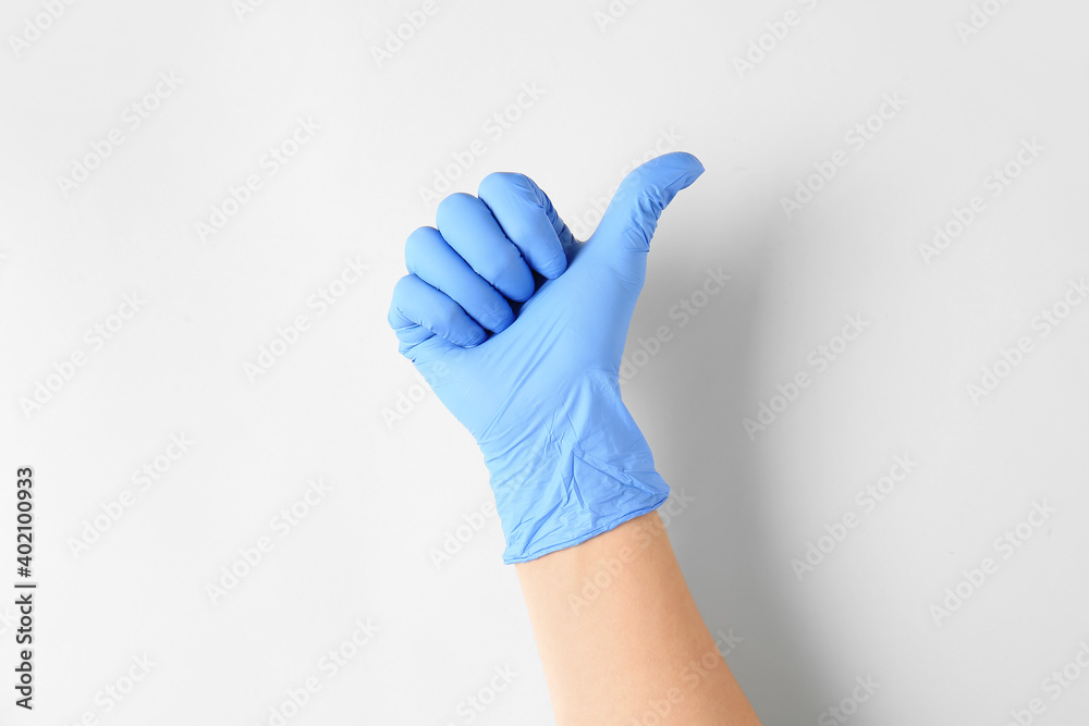 Hand in protective glove showing thumb-up on light background Hand in protective glove showing thumb-up on light background