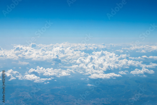 Blue sky with large beautiful clouds and a top view of the earth on a bright sunny day from the window of a flying plane. Sky replacement template