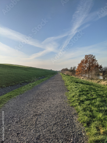 Photo A beautiful cloudscape over a gravel walkway at daytime in Emden, Germany