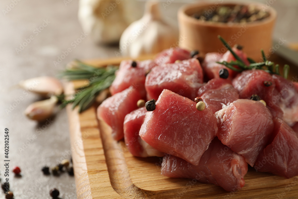 Board with raw meat, herbs and spices on gray background Board with raw meat, herbs and spices on gray background