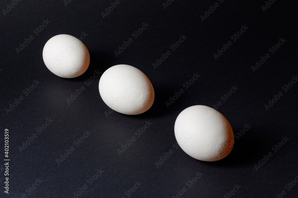 Three white eggs on a black background, dietary and healthy food rich in protein. Three white eggs on a black background, dietary and healthy food rich in protein.