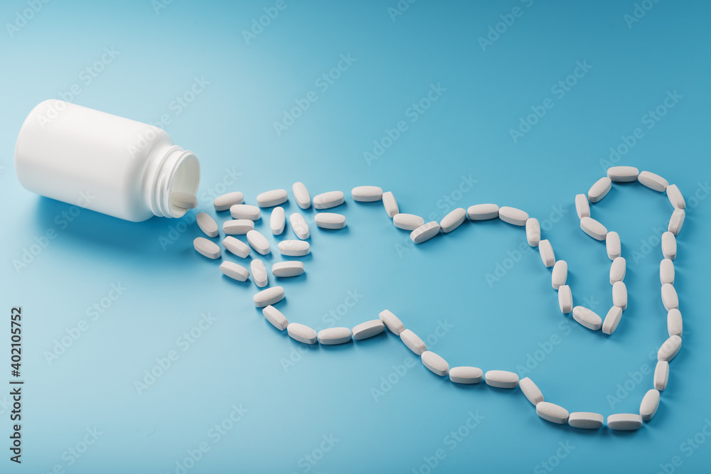 Biceps from white dragees with vitamins and minerals, Protein from a jar on a blue background.
