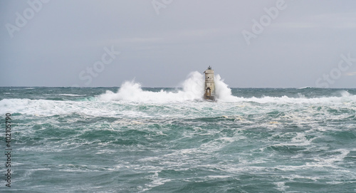 The lighthouse of the Mangiabarche shrouded by the waves of a mistral wind storm 