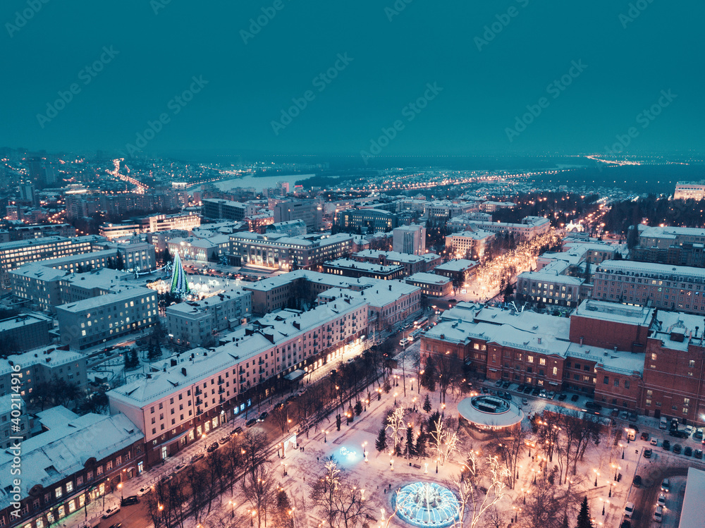 Aerial drone view of an evening city in winter with streets and intersections lit up and ready for Christmas celebrations
