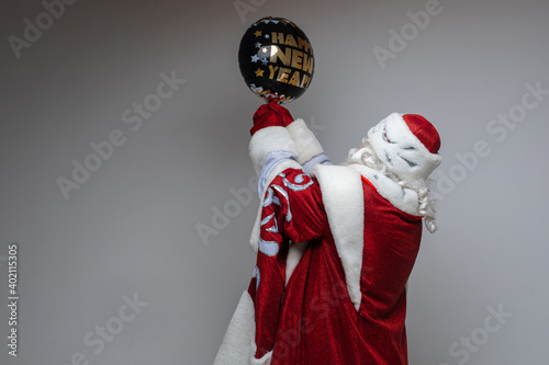 father frost holds a black christmas baloon, picture isolated on grey background