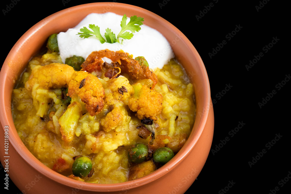 Delicious Daal Khichadi Also Known As Daliya Khichuri Or Dal Khichdi Sauteed With Indian Spices And Vegetables Served With Curd In Clay Pot Handi On Black Background With Copy Space For Custom Text Delicious Daal Khichadi Also Known As Daliya Khichuri Or Dal Khichdi Sauteed With Indian Spices And Vegetables Served With Curd In Clay Pot Handi On Black Background With Copy Space For Custom Text