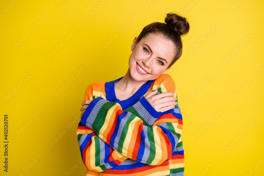 Portrait of funky pretty girl hugging herself wear rainbow sweater isolated on bright yellow color background Portrait of funky pretty girl hugging herself wear rainbow sweater isolated on bright yellow color background