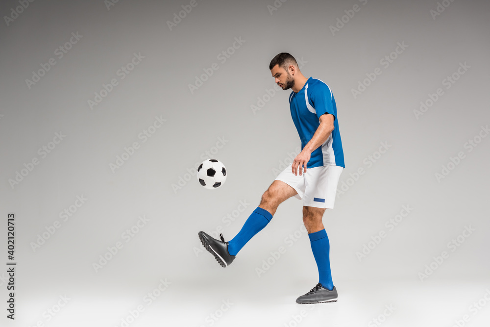 Man in sportswear playing soccer on grey background
