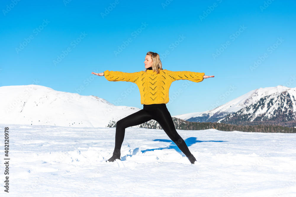 Woman practicing yoga in a landscape with snow in winter Woman practicing yoga in a landscape with snow in winter