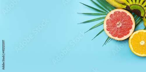 Fototapeta Naklejka Na Ścianę i Meble -  Tropical fruits summer banner background. Bananas, oranges and grapefruits on a colored blue background. Smoothie, summer vacation, sun and vitamins concept.