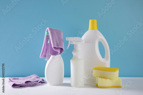 The bottles of sanitizers and sprays with sponges by a blue background