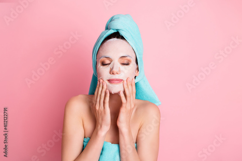 Portrait of young lovely happy positive girl enjoying face massage wear face nourishing mask isolated on pink color background