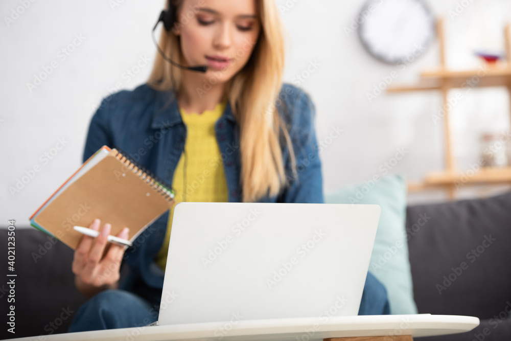woman holding pen and notebook near laptop at home on blurred background woman holding pen and notebook near laptop at home on blurred background