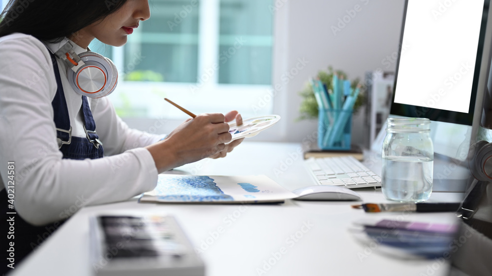 Side view of a female artist working on art projects on her studio. Side view of a female artist working on art projects on her studio.
