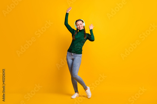 Full length body size photo female student in headphones listening music isolated on bright yellow color background © deagreez