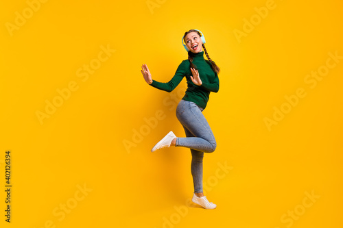 Full length body size photo funny woman listening blue earphones dancing looking blank space isolated on bright yellow color background