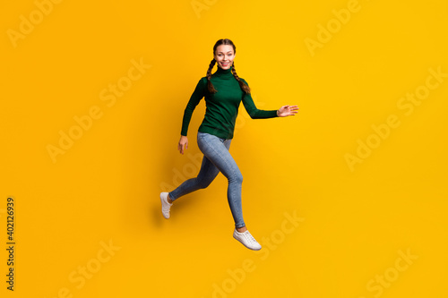 Full length body size photo smiling woman jumping high in casual clothes isolated on bright yellow color background