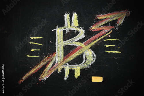Bitcoin cryptocurrency symbol with rising stocks arrow drawn on black chalkboard with yellow and red colorful chalk, blackboard texture and background, successful investment concept photo