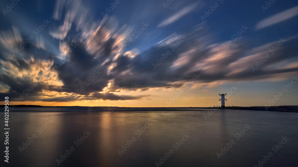 Vivid sunrise over pier and lighthouse in Swinoujscie, Poland.