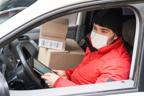 Delivery man wearing protective mask checking address of package