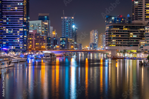 Night view to Dubai Marina panorama, reveals skyscrapers and beautiful bridge. Amazing colors reflect on the water. Luxury destination for tourists and residents. 