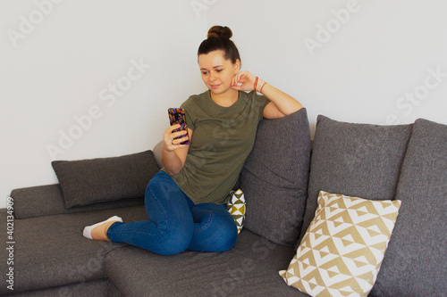 The girl sits on the couch and speaks on the phone. Overall plan