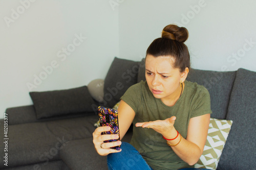 The girl sits on the couch and speaks on the phone. In a bad mood