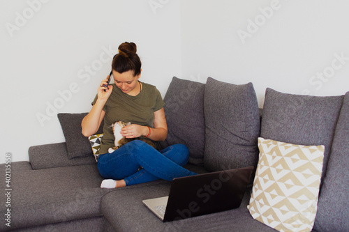 Girl at home working on a computer with a cat in her arms