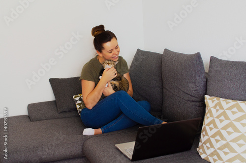 Girl at home working on a computer with a cat in her arms