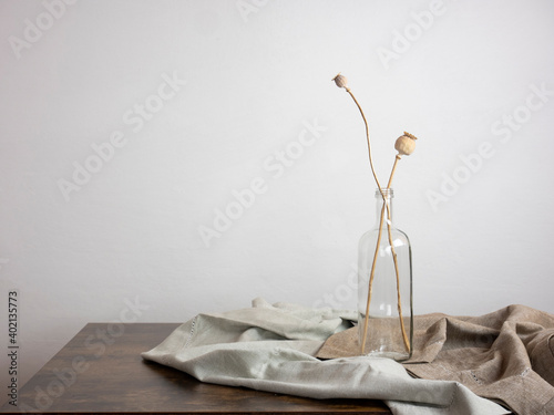 vintage interior design, dried poppy stems inside a bottle on the table, minimal style home ornament with copy space